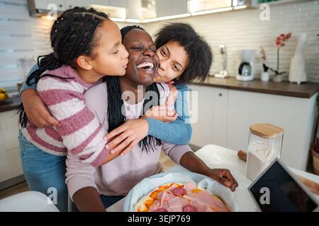 Mutter und Töchter küssen bei der Pizzazubereitung in der Küche Stockfoto