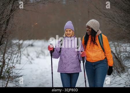 Verschiedene Freunde genießen Winterwanderungen mit Trekkingstöcken Stockfoto