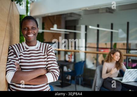 Glückliche junge Erwachsene Frau, die im Coworking Office steht Stockfoto