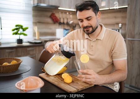 Mann, der erfrischende Limonade in die Küche gießt Stockfoto