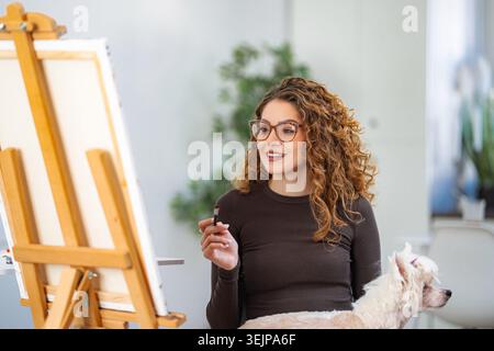 Künstlerin malte auf Leinwand mit Hund Stockfoto