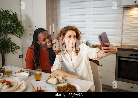 Verschiedene Freunde machen Selfie während einer gemeinsamen Mahlzeit zu Hause Stockfoto