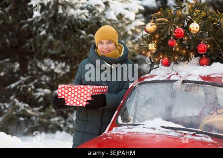 Ältere Frau in warmen Winterkleidung mit Weihnachtsgeschenk auf der Straße. frohe Weihnachten! Stockfoto