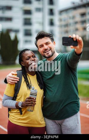 Glückliches interrassisches Paar, das Selfie auf der Laufbahn macht Stockfoto