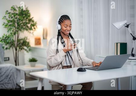 Junge schwarze Frau, die Musik hört, während sie von zu Hause aus arbeitet Stockfoto