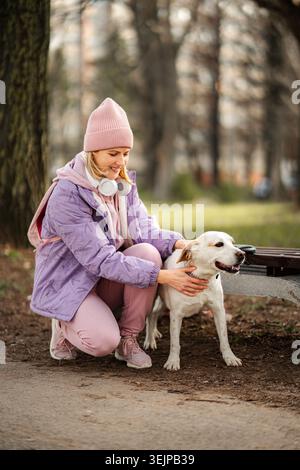 Frau streichelt glücklichen Hund im Park während des Winterwanderns Stockfoto
