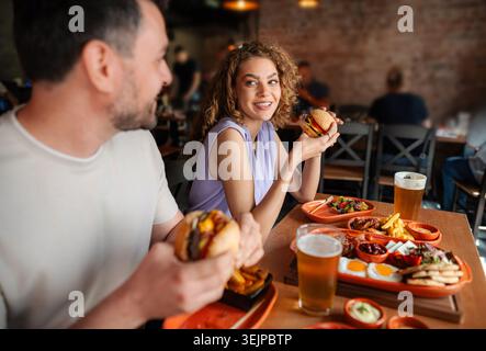 Ein Paar isst Burger und trinkt Bier im Restaurant Stockfoto