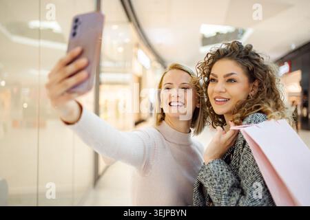 Glückliche Freundinnen, die Selfie im Einkaufszentrum machen Stockfoto