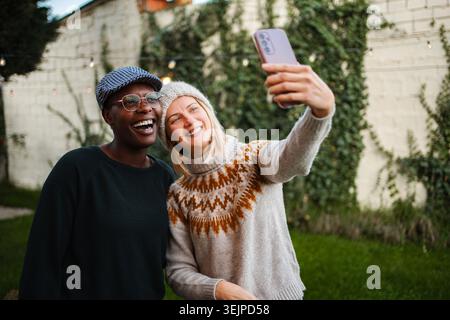 Glückliche Freundinnen, die ihr Smartphone für Selfie im Freien nutzen Stockfoto