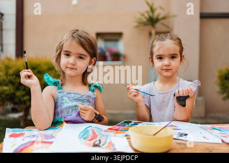 Zwei Mädchen im Vorschulalter malen mit Aquarellen im Garten Stockfoto