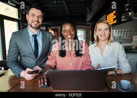 Vielseitiges Geschäftsteam, das mit Technologie im Café zusammenarbeitet Stockfoto