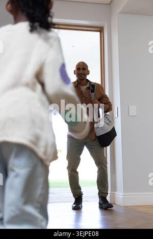 Vielfältige Papa-und-Kind-Begrüßung im Hauseingang, Vater trägt eine Seeschiffle, Kind trägt einen geflickten Pullover. Vater, Tür, Tasche, Stiefel, s Stockfoto