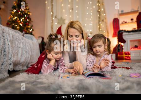 Mutter liest ihren Töchtern eine Weihnachtsgeschichte vor Stockfoto