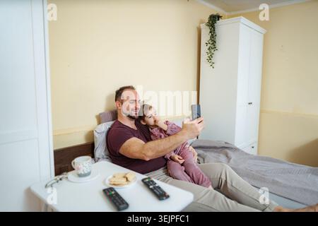 Vater-Tochter-Bonding macht ein Selfie im Bett Stockfoto
