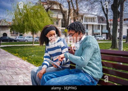 Zwei junge Erwachsene Freunde zeigen auf ein digitales Tablet Stockfoto