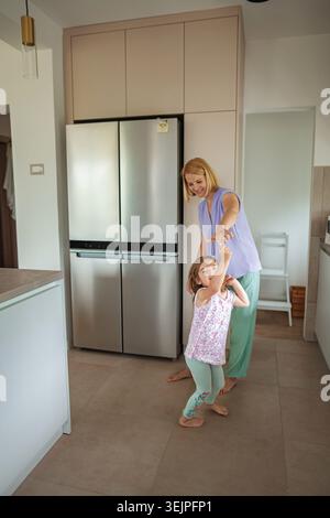 Eine Mutter tanzt mit ihrer Tochter in einer stilvollen Küche Stockfoto