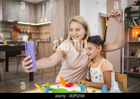 Mutter und Tochter genießen einen spielerischen Moment während sie ein Selfie machen Stockfoto