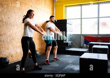 Zwei Personen, die mit Kettlebells trainieren, trainieren in einem Indoor Gym Stockfoto