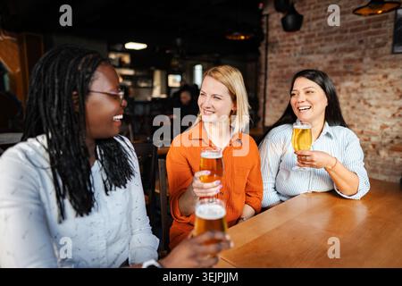 Verschiedene Freunde genießen Bier und lachen in der Bar Stockfoto