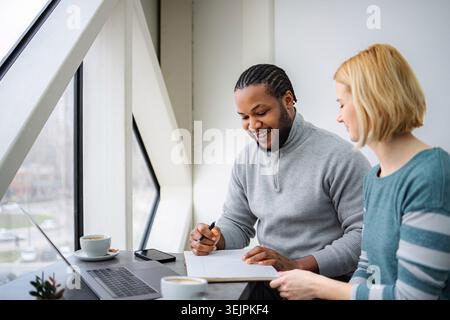 Zwei verschiedene Erwachsene arbeiten zusammen in einem Café, Planungsstrategie Stockfoto