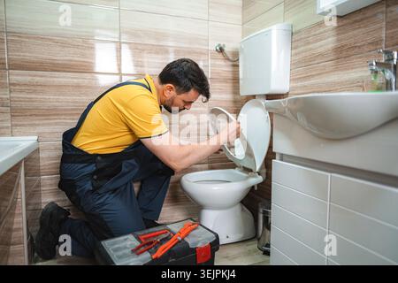 Klempner, der auf einer Toilette im Badezimmer arbeitet Stockfoto
