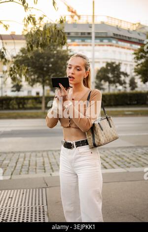 Junge Frau, die sich auf der Straße in Wien schminkt Stockfoto