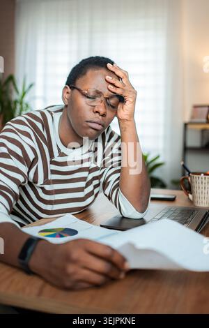 Junge erwachsene Frau mit Stress und Kopfschmerzen während der Heimarbeit Stockfoto