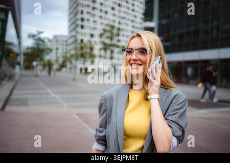 Lächelnde Geschäftsfrau, die in der Stadt am Handy spricht Stockfoto