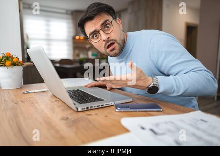 Mann in blauem Pullover, der auf Laptop schaut Stockfoto