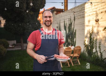 Am Abend treffen Sie sich im Hinterhof mit einem lächelnden Koch, der das Abendessen zubereitet Stockfoto