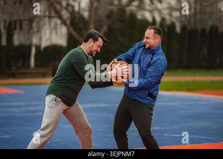 Zwei Männer kämpfen um Basketball auf dem Platz im Freien Stockfoto