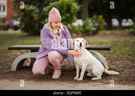 Frau streichelt glücklichen Hund im Park während des Spaziergangs Stockfoto