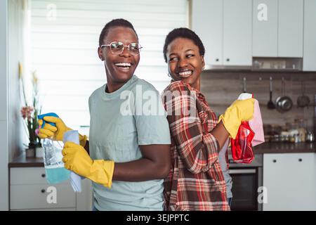 Zwei fröhliche schwarze Frauen putzen die Küche zusammen Stockfoto