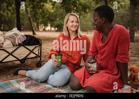 Zwei Freunde genießen ein Picknick im Park, trinken und plaudern Stockfoto