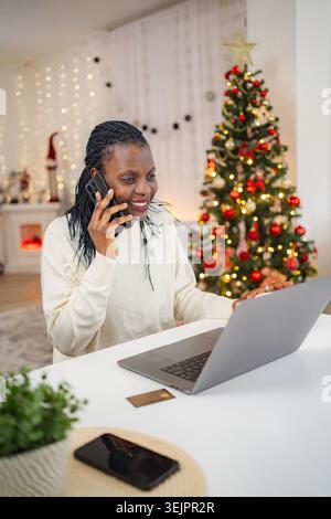 Afroamerikanerin telefoniert und Weihnachtseinkäufe im Internet Stockfoto