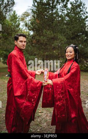 Ein Paar feiert eine interkulturelle Hochzeit in traditioneller chinesischer Kleidung Stockfoto