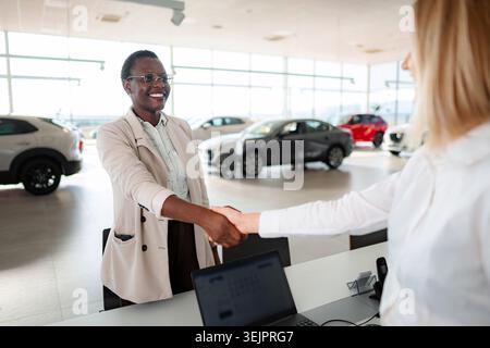 Zufriedener Kunde schüttelt sich die Hände mit dem Autoverkäufer im Händlerbetrieb Stockfoto