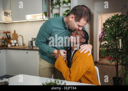 Interrassisches Paar teilt einen intimen Stirnkuss in der Küche Stockfoto