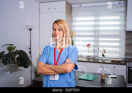 Ernsthafter Arzt posiert mit überkreuzten Armen in der modernen Klinikküche Stockfoto