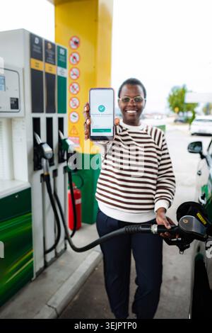 Frau, die Auto betankt und erfolgreich an der Tankstelle bezahlt Stockfoto