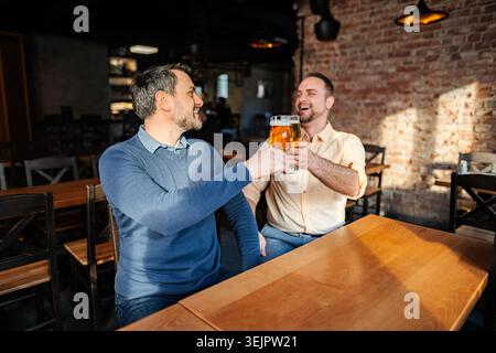 Zwei glückliche Männer, die im Pub mit Bier tosten Stockfoto