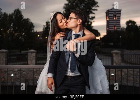 Interrassisches Hochzeitspaar, das sich bei Sonnenuntergang umschließt und küsst Stockfoto