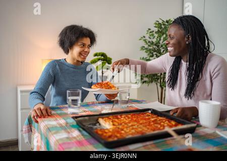 Mutter servierte der Tochter Pizza beim Abendessen zu Hause Stockfoto