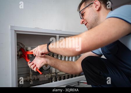 Klempner arbeiten an einem Rohrsystem in einem weißen Schrank Stockfoto