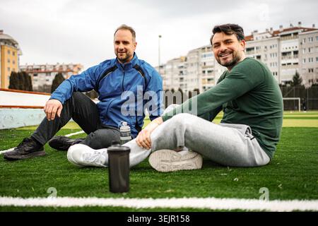 Zwei Erwachsene Männer ruhen sich nach dem Training auf dem Feld aus Stockfoto