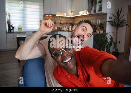 Glückliches Multi-ethnisches Paar, das ein Selfie macht, während es zu Hause Spaß hat Stockfoto