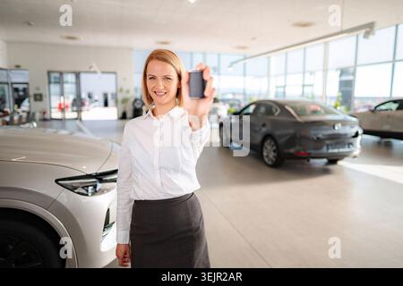 Frau, die im Ausstellungsraum einen neuen Autoschlüssel hält Stockfoto