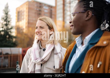 Verschiedene Freundinnen laufen zusammen im Freien und lächeln Stockfoto