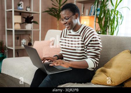 Junge Erwachsene Frau, die von zu Hause aus mit einem Laptop arbeitet Stockfoto