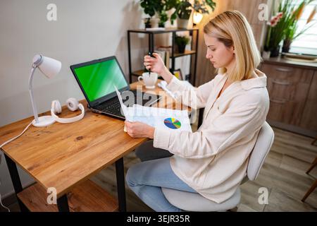 Fokussierte professionelle Analyse von Daten an einem modernen Arbeitsplatz zu Hause Stockfoto